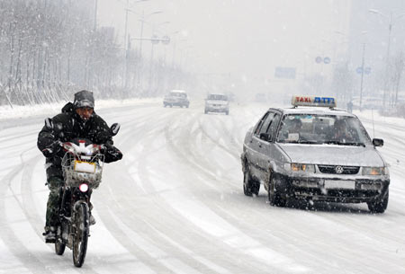 Vehicles run in snow on a snow-covered road in Shenyang, capital of northeast China&apos;s Liaoning Province, on Nov. 13, 2009. The heaviest snowfall this winter hit Liaoning Province since the afternoon of Nov. 12. [Xinhua]