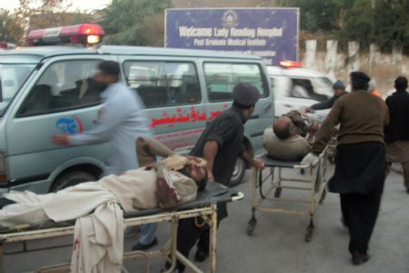 People carry men injured in a blast in Peshawar, Pakistan, Nov. 13, 2009.[Xinhua]