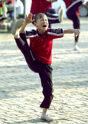 He Minxian, a 9-year-old kid, practise basic skills during a team training class in the Shaolin Tagou Kung Fu (Martial Art) Institute at the foot of Mountain Song in Dengfeng, a city of central China&apos;s Henan Province, Oct. 12, 2009.[Wang Song/Xinhua]