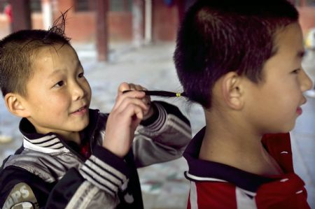 He Minxian (L), a 9-year-old kid, makes a braid for a classmate in the Shaolin Tagou Kung Fu (Martial Art) Institute at the foot of Mountain Song in Dengfeng, a city of central China&apos;s Henan Province, Oct. 12, 2009.[Wang Song/Xinhua]