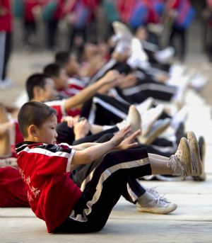 He Minxian (Front), a 9-year-old kid, and his classmates practise to enhance strength in the Shaolin Tagou Kung Fu (Martial Art) Institute at the foot of Mountain Song in Dengfeng, a city of central China&apos;s Henan Province, Oct. 12, 2009.[Wang Song/Xinhua]