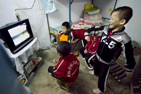 He Minxian (R), a 9-year-old kid, and his classmates watch TV in their dormitary of the Shaolin Tagou Kung Fu (Martial Art) Institute at the foot of Mountain Song in Dengfeng, a city of central China&apos;s Henan Province, Oct. 12, 2009.[Wang Song/Xinhua]