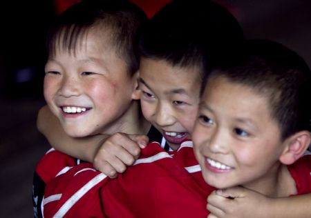 He Minxian (L), a 9-year-old kid, and his classmates watch reporting performance of students of high grades in the Shaolin Tagou Kung Fu (Martial Art) Institute at the foot of Mountain Song in Dengfeng, a city of central China&apos;s Henan Province, Oct. 12, 2009.[Wang Song/Xinhua]