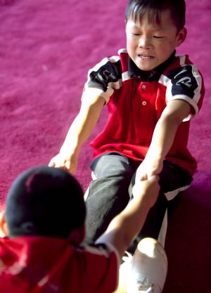 He Minxian (Top), a 9-year-old kid, and his classmates stretch themselves in the Shaolin Tagou Kung Fu (Martial Art) Institute at the foot of Mountain Song in Dengfeng, a city of central China&apos;s Henan Province, Oct. 12, 2009.[Wang Song/Xinhua]