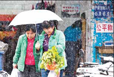 Two women carry vegetables home from a market in Beijing. The prices of vegetables remained stable in the capital but they have increased in some other cities as heavy snow raised the transportation cost. [Luo Xiaoguang]