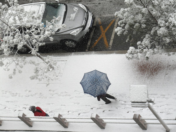 People walk in snow on a snow-covered road in northeast China's Jilin Province, on Nov. 13, 2009. [CFP]