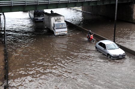 Vehicles run slowly on a flooded road in Buenos Aires, capital of Argentina, on Nov. 14, 2009. [Niceto Vega/Xinhua]