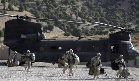 U.S. soldiers from Task Force Geronimo walk in front of a Chinook CH-47F transport helicopter while on their way to a new location, at FOB Tillman, Afghanistan, November 15, 2009. [Xinhua/Reuters]