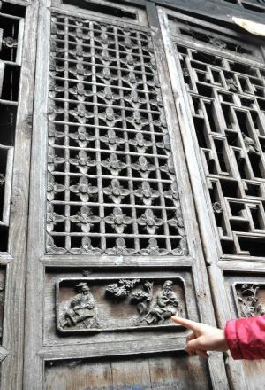 Photo taken on Nov. 15, 2009 shows a visitor points at a carved wooden door of the Ming Dynasty at Fuxi Village with lots of ancient architectures that date to the Ming and Qing Dynasties in Fuchuan Yao Autonomous County, southwest China&apos;s Guangxi Zhuang Autonomous Region. [Xinhua]