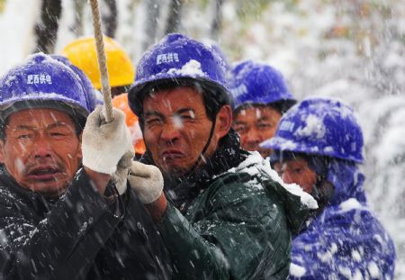 Rescue workers pull while repairing the broken local electrical system amid a heavy snowfall in Feixi county, east China&apos;s Anhui Province Nov. 16, 2009. Most parts of Anhui Province were swept by since Sunday night.[Xinhua]
