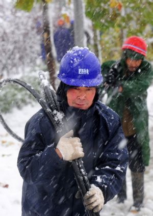 Rescue workers carry wires while repairing the broken local electrical system amid a heavy snowfall in Feixi county, east China&apos;s Anhui Province Nov. 16, 2009.[Xinhua] 