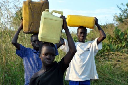 Denis Opoka (1st R) and his brother and sister carry water home at Ajulu village, in Gulu district, northern Uganda, on Oct. 20, 2009. [Tian Ye/Xinhua]