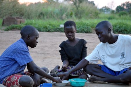  Denis Opoka (1st R) and his brother and sister have meal at Ajulu village, in Gulu district, northern Uganda, on Oct. 20, 2009. [Tian Ye/Xinhua]