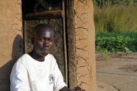 Denis Opoka sits in front of his hut at Ajulu village, in Gulu district, northern Uganda, on Oct. 20, 2009. [Tian Ye/Xinhua]