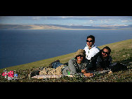 Three foreign tourists take photos at their ease on the shore of Lake Nam Co. [Photo by Fanlin]