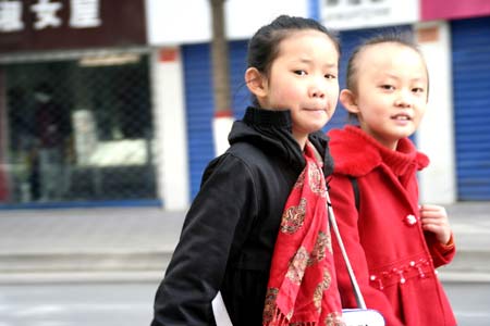  Two girls walk on street in downtown Xining looking at the camera curiously on Oct. 31, 2009. [Xinhua]