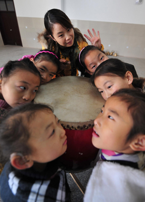 Deaf-mute students put their faces against a drum to feel the rhythm during a dance class at a special education school in Yichang City, Central China&apos;s Hubei province, November 19, 2009.[Xinhua]