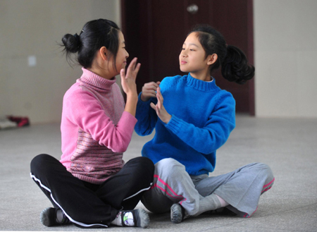 Deaf-mute students Liu Yidan (L) and Luo Yanan (R) communicate through sign language during a dance class at a special education school in Yichang City, Central China&apos;s Hubei province, November 19, 2009. [Xinhua]