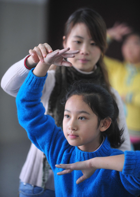 Teacher Feng Yan (Back) corrects the posture of a deaf-mute student Liu Yidan (L) during a dance class at a special education school in Yichang City, Central China&apos;s Hubei province, November 19, 2009. [Xinhua]