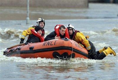 Rescue services workers transporting flood victims to safety navigate the flood waters in the streets of Cockermouth village, England, Friday, Nov. 20, 2009. The Royal Air Force and Royal National Lifeboat Institution (RLNI) rescue services have joined efforts to rescue stranded residents from their homes, after heavy rains caused local flooding in the picturesque north England village. Around 200 people was stranded by rising floodwater in the northern England tourist town. [Scott Heppell/AP]