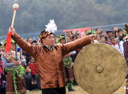 A man beats the gong to pray for good luck and bumper harvest during the Lusheng and Horse Fight Festival held in the Sports Park in Rongshui Miao Autonomous County, southwest China's Guangxi Zhuang Autonomous Region, Nov. 21, 2009.(Xinhua/Long Tao)