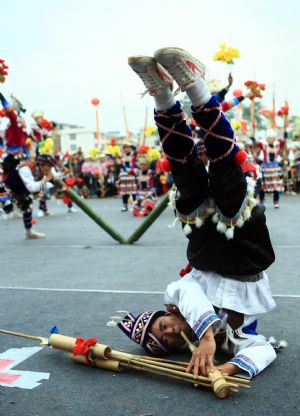 A performer plays the lusheng musical pipe during the Lusheng and Horse Fight Festival held in the Sports Park in Rongshui Miao Autonomous County, southwest China's Guangxi Zhuang Autonomous Region, Nov. 21, 2009.(Xinhua/Long Tao)