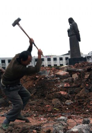 A worker hammers the ground beside the bronze statue of Lin Zexu on the Lin Zexu Square under project of overall renovation, in the downtown of Fuzhou City, southeast China's Fujian Province, Nov. 21, 2009.(Xinhua/Zheng Shuai)