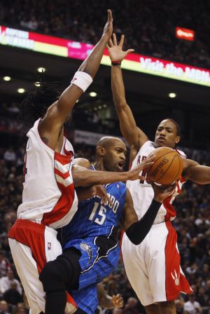 Orlando Magic's Vince Carter goes to the basket against Toronto Raptors' Chris Bosh and DeMar DeRozan (R) during the second half of their NBA basketball game in Toronto, November 22, 2009. Magic beats Raptors with 104-96.(Xinhua/Reuters Photo)