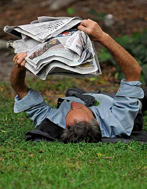 A city worker is seen reading the paper in the shade during a hot day in Sydney, Australia, on Nov. 20, 2009.(Photo Source: CRIENGLISH.COM/AFP Photo)