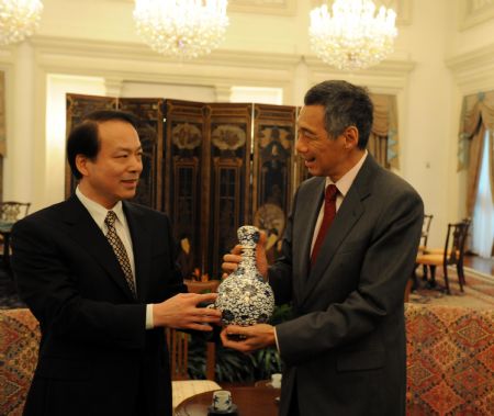 Singapore's Prime Minister Lee Hsien Loong (R) receives a gift presented by He Ping, editor-in-chief of China's Xinhua News Agency, during their meeting in Singapore Nov. 23, 2009. (Xinhua/Zhang Yongxing) 