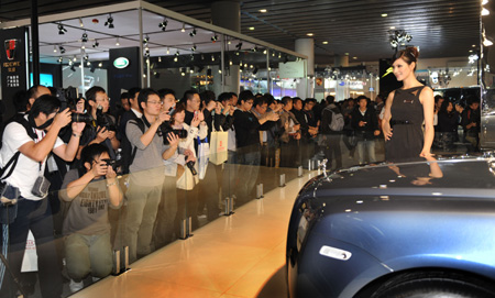 Visitors take photos of a model standing next to a Rolls-Royce car during the 7th Guangzhou International Auto Show opened in Guangzhou, south China's Guangdong Province, Nov. 24, 2009. Some 720 automibles from over 60 auto makers are on show.
