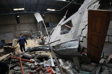 A Palestinian inspects a factory's workshop destroyed in an Israeli air strike near the border between Egypt and the southern Gaza Strip November 24, 2009.(Xinhua/AFP Photo)