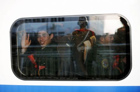 An armed policeman who has retired waves from a train at a railway station in Taiyuan, capital of north China's Shanxi Province, Nov. 25, 2009.(Xinhua/Yan Yan)