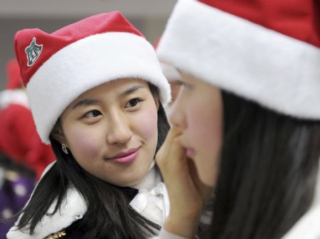 A participant dressed in a Santa Claus outfit puts on make up for her colleague during a promotional event for the Christmas holiday season at the Everland amusement park in Yongin, about 50 km (31 miles) south of Seoul, November 25, 2009.(Xinhua/Reuters Photo)