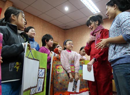 Anna Mare Holm, a Danish female acts artist, talks to a group of pupils who practise with their children's paintings, during an activity on the Fairy Tale World of the Children Heart, Genuine Nature and Fun, at the Hepingli Elementary School No.1, of Beijing, Nov. 25, 2009. (Xinhua/Zhou Liang)