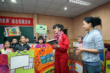 Anna Mare Holm, a Danish female acts artist, talks to a group of pupils who practise with their children's paintings, during an activity on the Fairy Tale World of the Children Heart, Genuine Nature and Fun, at the Hepingli Elementary School No.1, of Beijing, Nov. 25, 2009. (Xinhua/Zhou Liang)