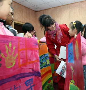 Anna Mare Holm, a Danish female acts artist, talks to a group of pupils who practise with their children's paintings, during an activity on the Fairy Tale World of the Children Heart, Genuine Nature and Fun, at the Hepingli Elementary School No.1, of Beijing, Nov. 25, 2009. (Xinhua/Zhou Liang)