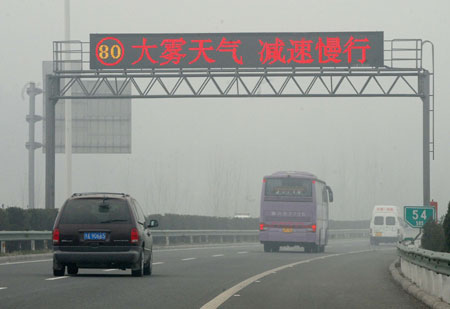 Vehicles move in the fog in Zhengzhou, capital of central China&apos;s Henan Province, Nov. 26, 2009. The city witnesses the dense fog in the past 3 days. (Xinhua/Wang Song)