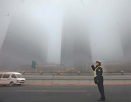 A police officer directs traffic amid the fog in Chaoyang district yesterday. [Mirror Evening News]