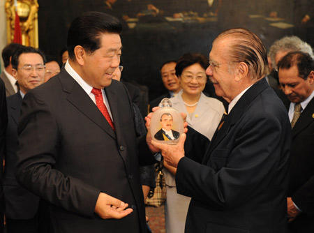 Jia Qinglin (L), chairman of the National Committee of the Chinese People&apos;s Political Consultative Conference, presents a gift to Brazilian Federal Senate President Jose Sarney (R) during their meeting in Brasilia on Nov. 26, 2009. [Li Xueren/Xinhua]