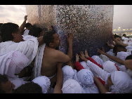 Muslim pilgrims touch the Jabal al-Rahma pillar on Mount Mercy on the plains of Arafat outside the holy city of Mecca November 26, 2009.[Xinhua]