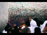 Muslim pilgrims touch the Jabal al-Rahma pillar on Mount Mercy on the plains of Arafat outside the holy city of Mecca November 26, 2009.[Xinhua]