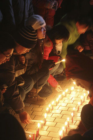 People light up candles to pray for the dead miners of a coal mine accident at the Zhenxing Square in Hegang City, northeast China&apos;s Heilongjiang Province, Nov. 25, 2009. Hundreds of people gathered at the square to mourn for the miners dead in the accident occurring in the Xinxing Coal Mine on Nov. 21. An explosion in the mine caused 92 miners dead and 16 others still missing. [Bai Changhai/Xinhua]