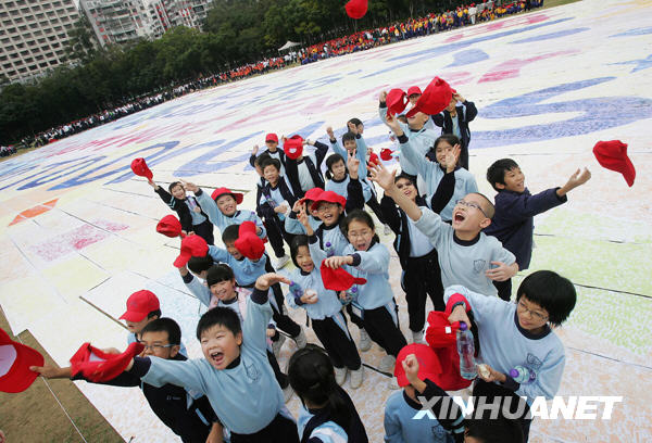  A group of pupils celebrate after finishing making the giant finger painting at Victoria Park in Hong Kong on Thursday, November 26, 2009. [Xinhua]