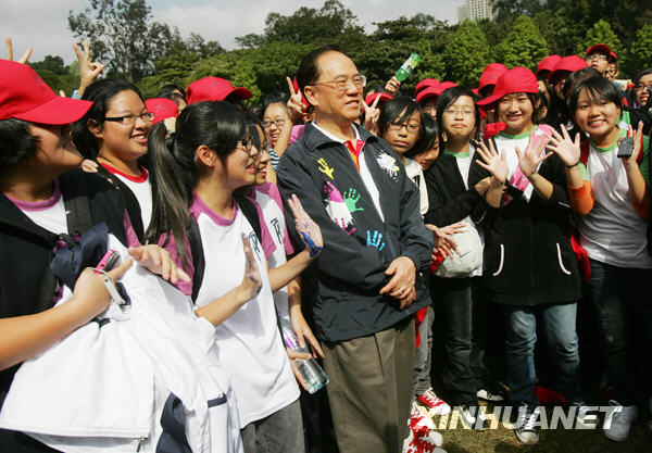 Chief Executive of Hong Kong Special Administrative Region Donald Tsang poses for photos with students who made the giant finger painting at Victoria Park in Hong Kong on Thursday, November 26, 2009. [Xinhua]