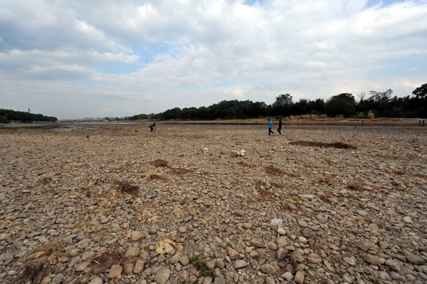 Tourists walk on the bared riverbed of Lijiang River. Nov. 8, 2009. [Chen Ruihua/Xinhua]