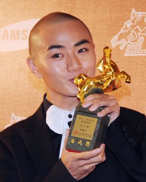 Chinese actor Yu Shaoqun kisses his award for Best New Performer for the film 