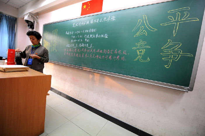 A invigilator waits in a classroom before the servant recruitment exam starts at Beijing No. 171 High School, Nov. 29. Almost 1 million people Sunday sat China&apos;s national examination for 2010 admissions to the civil service. [Xinhua]
