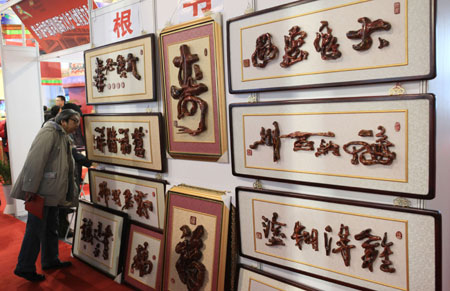 An old visitor admires some articles of "Root Calligraphy" at the 4th Bejing Cultural and Creative Fair in Beijng, the capital city of China on Nov. 28, 2009. The fair, which was kicked off on Saturday, exhibited various strange and interesting cultural creations and attracted a great number of visitors.