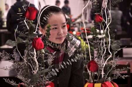 A visitor appreciates ikebana works during the 2nd Wuhu ikebana contest held in Wuhu city, east China's Anhui Province, Nov. 29, 2009. Fifty-eight contestants took part in the ikebana theoretics and skill contest on Sunday. The first prize winner of the contest will receive skill topmost master certificate and trophy from local labor administrative department. 